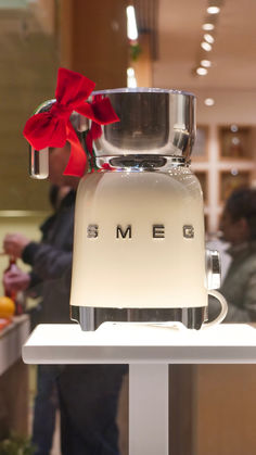 a white blender sitting on top of a table with a red bow around it