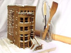 a gingerbread house is decorated with icing and snow, next to a whisk mixer