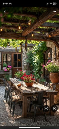 an outdoor dining table with chairs and potted plants on the table in front of it