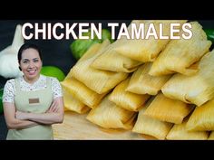 a woman standing in front of a pile of tamales