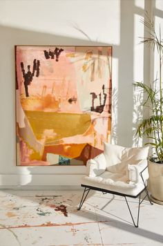 an image of a living room with a painting on the wall and a chair in front of it