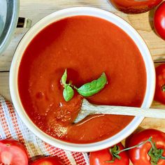 a white bowl filled with tomato sauce next to tomatoes