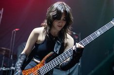 a woman holding a bass guitar on stage