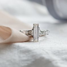 a diamond ring sitting on top of a white cloth