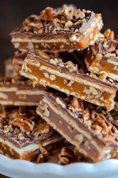 a white plate topped with pieces of chocolate covered pretzel barkle bars filled with nuts