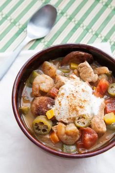 a bowl filled with meat and vegetables next to a spoon on top of a table