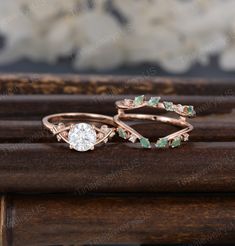 two wedding rings with green and white stones on the top, one in rose gold