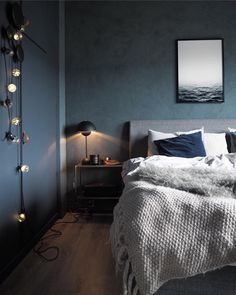 a bed sitting in a bedroom next to a wall with lights on top of it