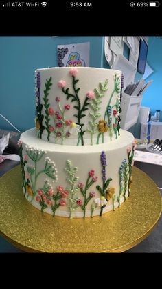 a three layer cake decorated with flowers on a gold platter