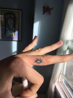 two fingers that are touching each other in front of a window with the sun on it