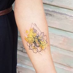 a woman's arm with a tattoo on it that has a bee and geometric shapes