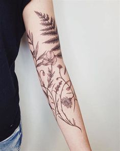 a woman's arm with flowers and leaves tattooed on the left side of her arm