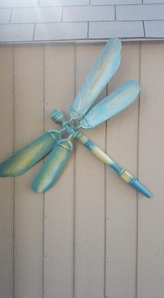 a blue dragonfly is hanging on the side of a building with its wings spread out