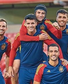 a group of men standing next to each other in front of a soccer ball field