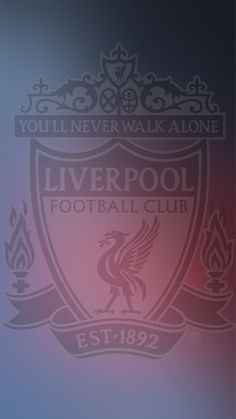 the liverpool football club logo is shown on a blurry background with red and blue colors