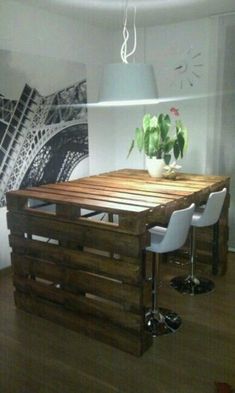 a table made out of wooden pallets with white chairs and a plant on top