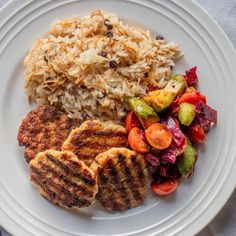 a white plate topped with meat, rice and veggies next to a fork