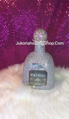 a bottle with some glitter on it sitting in front of a purple sequin backdrop