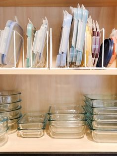 the shelves are filled with glass dishes and plastic containers on them, including one for food storage