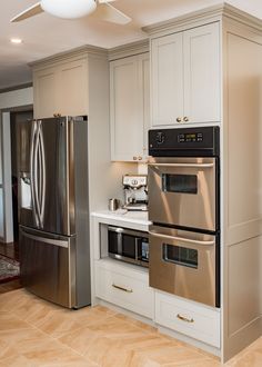 a modern kitchen with stainless steel appliances and white cabinets, along with hardwood flooring