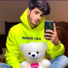 a man in a yellow hoodie holding a white teddy bear