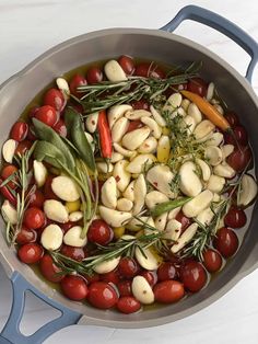 a pan filled with olives, tomatoes and herbs