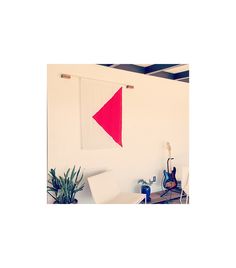 an office with a desk, chair and red triangle hanging on the wall above it