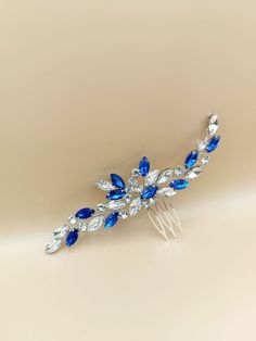 Enhance your special day with a touch of elegance using our luxurious blue hair comb! Handmade with exquisite craftsmanship, this stunning blue hair accessory is adorned with glistening crystal rhinestones delicately intertwined with jewelry wire. Measuring approximately 5 inches in length, this rhinestone hair comb serves as the perfect addition for weddings or proms, adding a sophisticated allure to any hairstyle. Its timeless design exudes grace and beauty, complementing a range of hairdos. Elevate your look and capture the essence of elegance with this meticulously crafted accessory. Whether it's for your wedding day or a glamorous prom night, this blue bridal comb is sure to make a statement. Versatile and adaptable, our stunning hair accessory is designed to effortlessly complement a Silver And Blue Hair, Blue Hair Piece, Royal Blue Hair, Navy Blue Hair, Blue Hair Accessories, Rhinestone Hair Comb, Bridal Hair Piece, Bridal Comb, Magical Jewelry