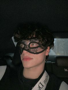 a man wearing a black mask in the back seat of a car