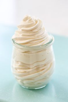 a glass jar filled with whipped cream sitting on top of a blue countertop next to a knife