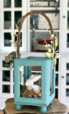 a small blue box with a bunny in it on top of a wooden table next to a white hutch