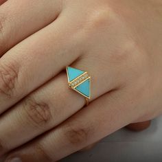 a woman's hand wearing a gold ring with blue stones on the band and a diamond in the middle