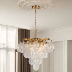 a chandelier hanging from the ceiling in a living room with white walls and curtains