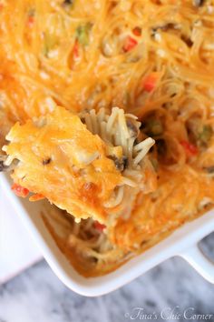 a casserole dish with noodles and vegetables in it on a white serving dish