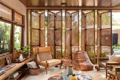 a living room filled with furniture and lots of windows covered in bamboo blinds, plants