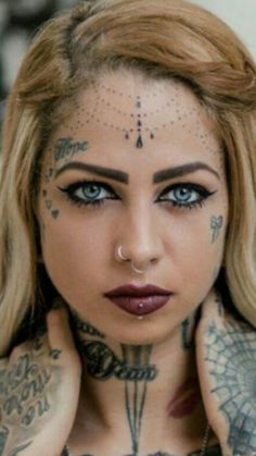 a woman with tattoos and piercings on her chest is looking at the camera while holding her hands behind her neck