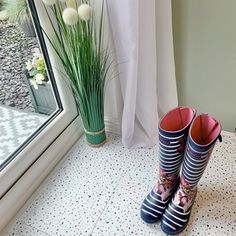 a pair of rain boots sitting on top of a tiled floor next to a window