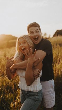 a man and woman standing in a field with their arms around each other