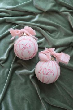 two pink ornaments with numbers on them are laying on a green cloth covered bed sheet