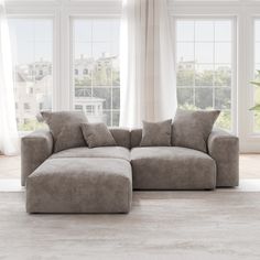 a large sectional couch in front of two windows