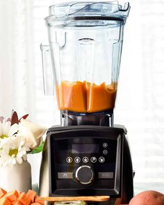 a blender filled with liquid sitting next to some vegetables and potatoes on a table