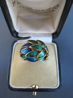 "This ring is pure poetry on the finger. Green and blue feathers are set in 18k gold in a dome shape across the top of the ring. Absolutely stunning on the finger. Very good vintage condition. No enamel loss! Some patina to the gold which is left for a buyer to clean if desired. NOTE: As with all enamel jewelry, care must be used when wearing an enamel piece. It's not recommended to wear enamel next to anything that can knock into it and break/crack the enamel. Avoid harsh chemicals and washing Antique Ring Box, Blue Feathers, Platinum Diamond Engagement Rings, Coral Ring, Dome Ring, Blue Feather, Enamel Ring, Domed Ring, Gold Enamel