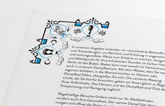 an open book with black and blue designs on the pages, including letters in different languages