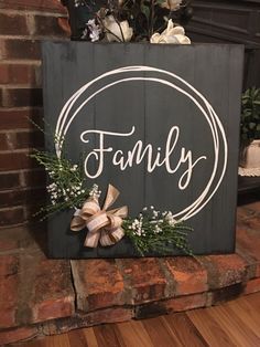 a sign that says family on it with flowers and greenery in front of a brick wall