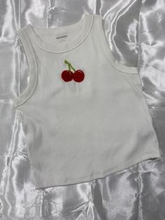 two cherries are attached to the back of a white tank top with satin material