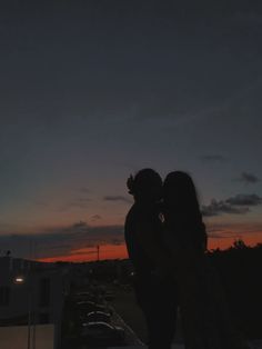 two people standing next to each other at sunset