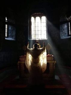 a person sitting on a bench in the dark with their arms outstretched and sunlight streaming through windows