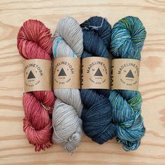 three skeins of yarn sitting next to each other on a wooden surface,