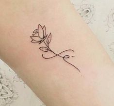 a small flower tattoo on the left side of the arm, with an arrow in the middle