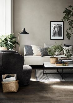 a living room filled with lots of furniture and plants on top of a table in front of a window